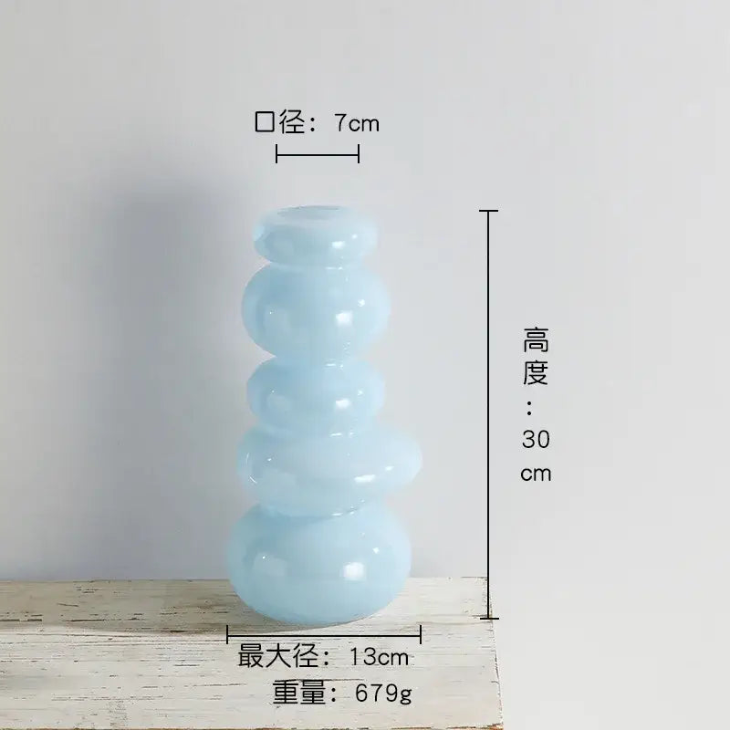 A translucent light blue glass vase with a stacked rounded design for pebble stack floral arrangement use