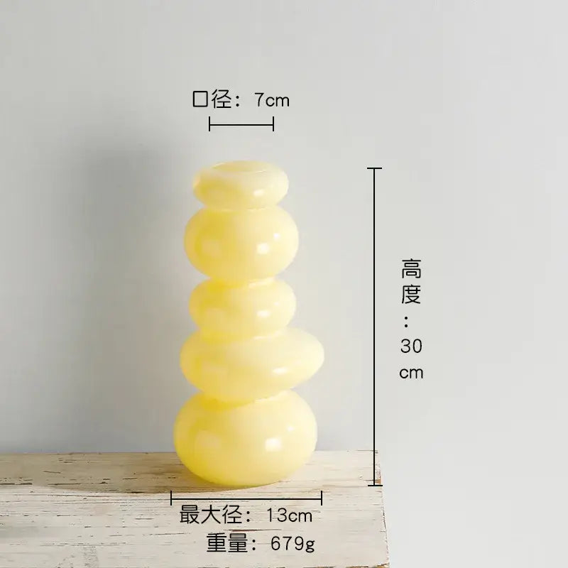 Glossy pastel pink vase with translucent yellow smooth pebble stack floral sculpture in rounded stacked tiers