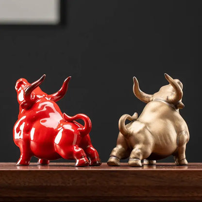 Two glossy ceramic bull figurines in vibrant red and metallic gold with detailed horns and tails for office decorbites bull figurine decor