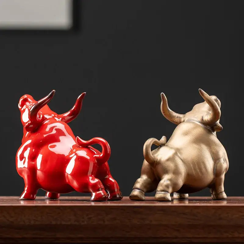 Two glossy ceramic bull figurines in vibrant red and metallic gold with detailed horns and tails for office decorbites bull figurine decor