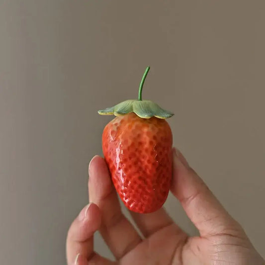 Glossy red ceramic strawberry fruit sculpture tea caddy with green leafy top and textured seed-like surface for kitchen decor