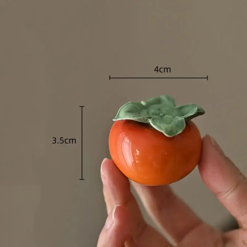 Glossy orange ceramic fruit sculpture tea caddy with green leafy top measuring 4cm wide and 3.5cm tall