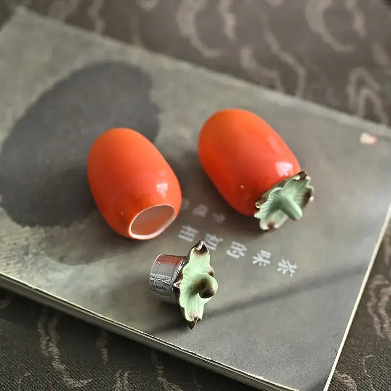 Vibrant orange ceramic persimmon fruit sculpture tea caddy with glossy finish and green leafy tops for kitchen decor