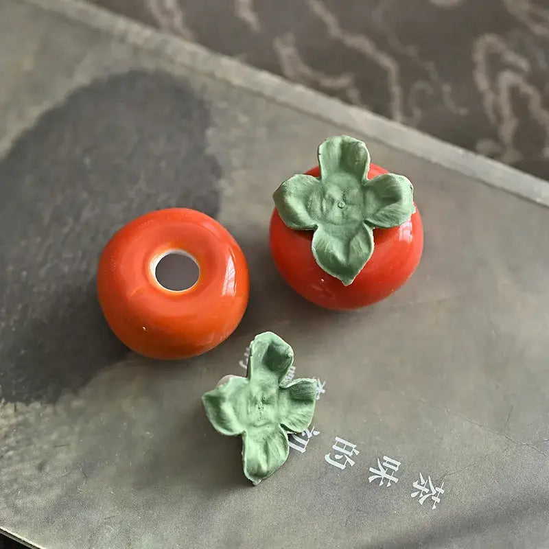 Glossy orange ceramic persimmon fruit sculpture tea caddy with green leaf accents for kitchen decor