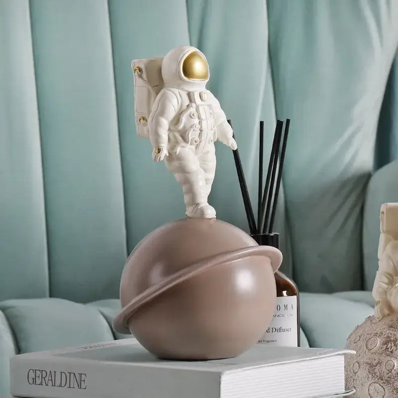 Glossy white and gold astronaut phone holder sculpture standing atop a matte taupe planet globe for bedroom decor