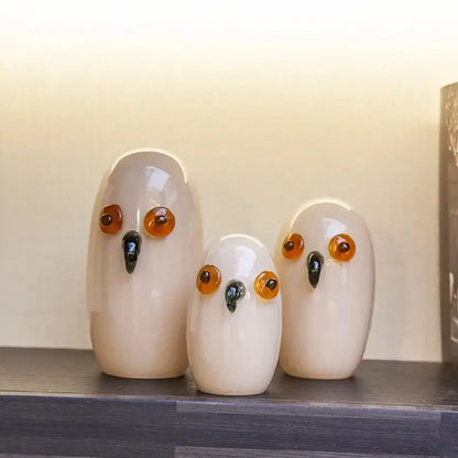 Three glossy white cartoon owl glass sculptures with amber eyes and black beaks for home decor by decorbites cartoon owl