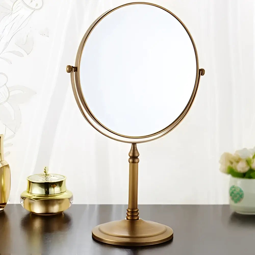 Brass double-sided vanity mirror with ornate frame and pedestal base in gold and black adjustable wall mounted cosmetic style