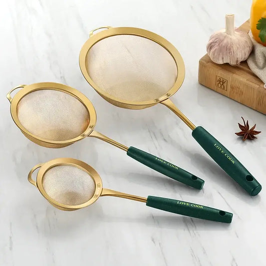 Set of three gold-finished metal kitchen colander juice strainers with dark green handles engraved with love cook