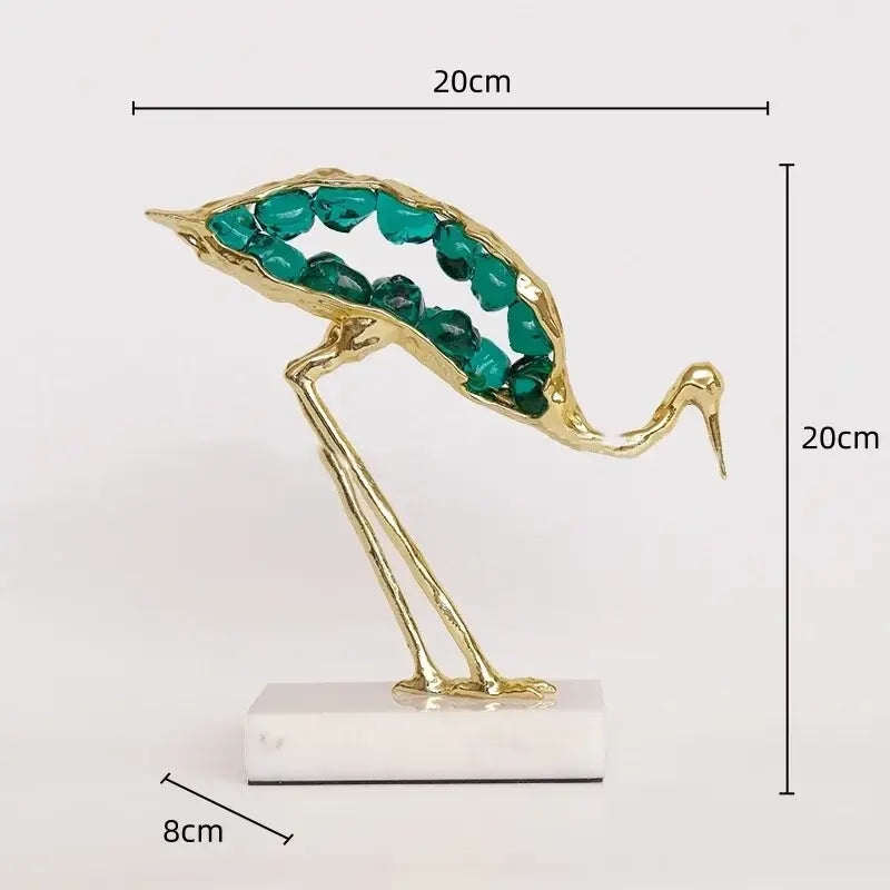 Gold and emerald crystal crane sculpture with golden body and teal gemstone details on white marble base for decor