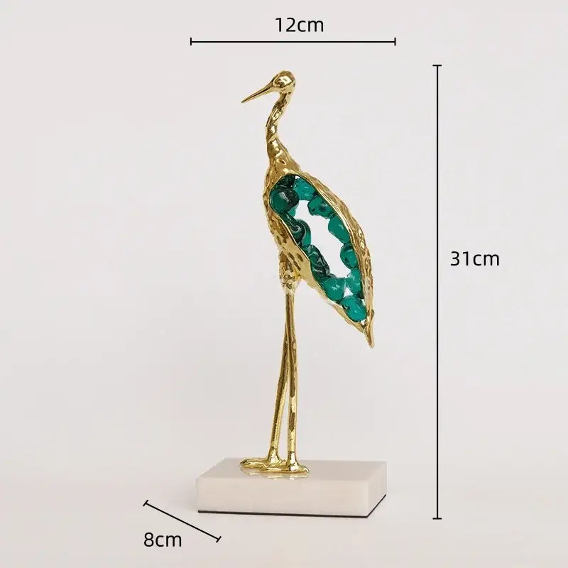 Gold and emerald crystal crane sculpture with emerald green gemstone wings on white marble base for living room decor