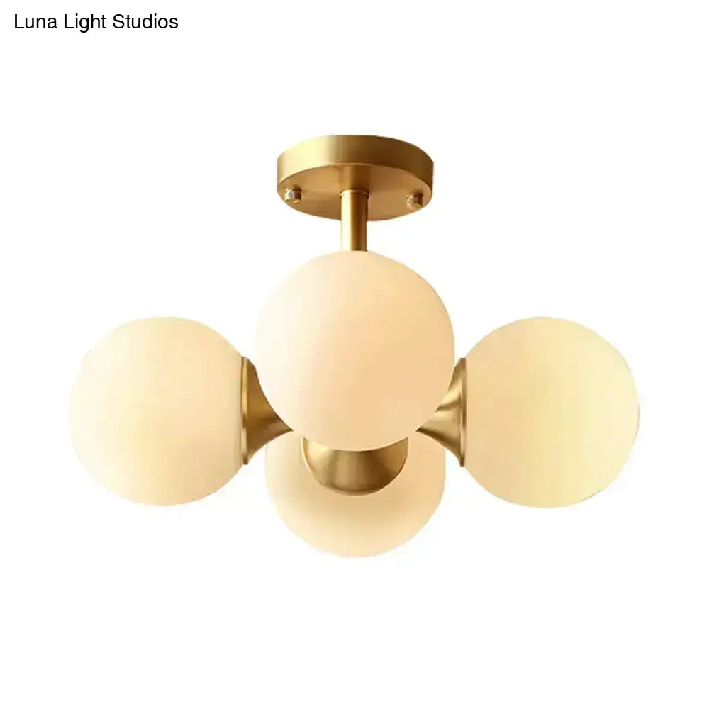 Gold-toned semi-flush mount ceiling fixture with four frosted opaline glass globes for 220v-240v 110v-120v use