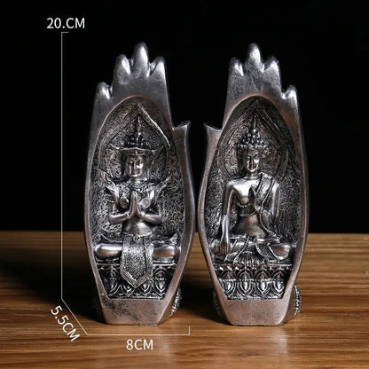 Silver-colored intricately detailed buddha hands monk figurine seated in open hand-shaped base for living room decor