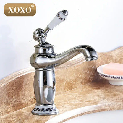 Chrome-finished deck mounted basin faucet with ornate white ceramic handle featuring black floral decorbites bathroom basin