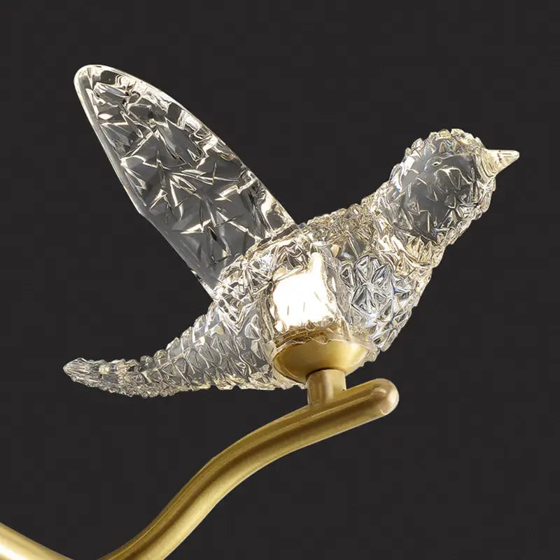 A gold bird branch led pendant lamp with clear crystal glass and a golden brass base designed for dining room use