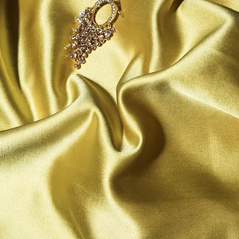 A sparkling gold earring with clear crystals complements the gold and black 200s embroidery egyptian cotton bedding set