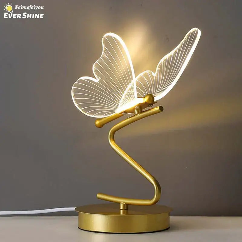 Gold butterfly led table lamp with illuminated translucent wings and sleek curved metallic base for bedroom decorbites butterfly led