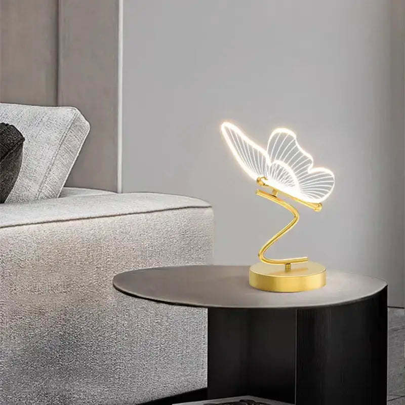 Gold-toned butterfly led table lamp with illuminated translucent wings and sleek curved base for bedroom decorbites butterfly led light
