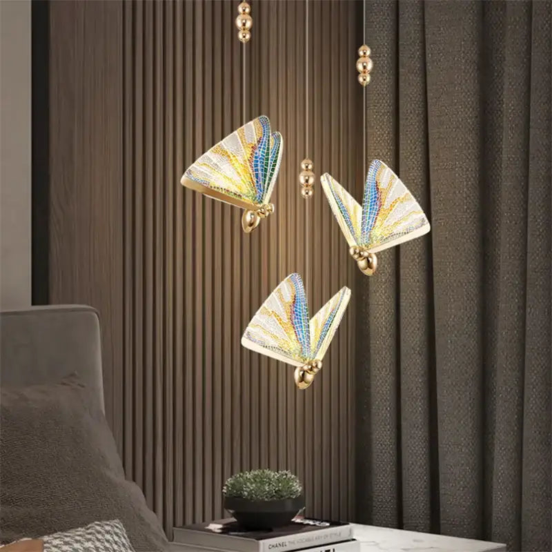 Three elegant gold butterfly pendant lights with acrylic elements and iridescent wings that work beautifully for bedroom use