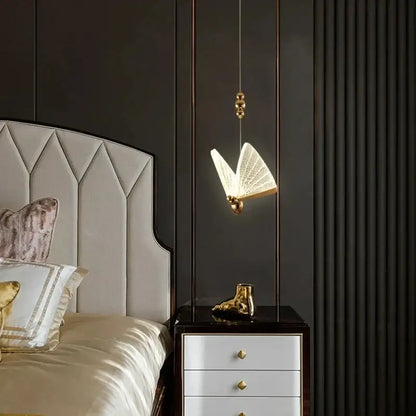Gold butterfly pendant light with acrylic elements and illuminated open-wing design works beautifully above nightstand