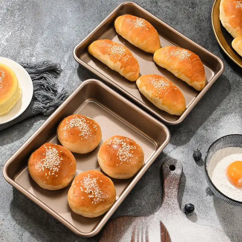 Two gold decorbites carbon steel baking trays with non stick matte bronze finish holding sesame topped baked goods