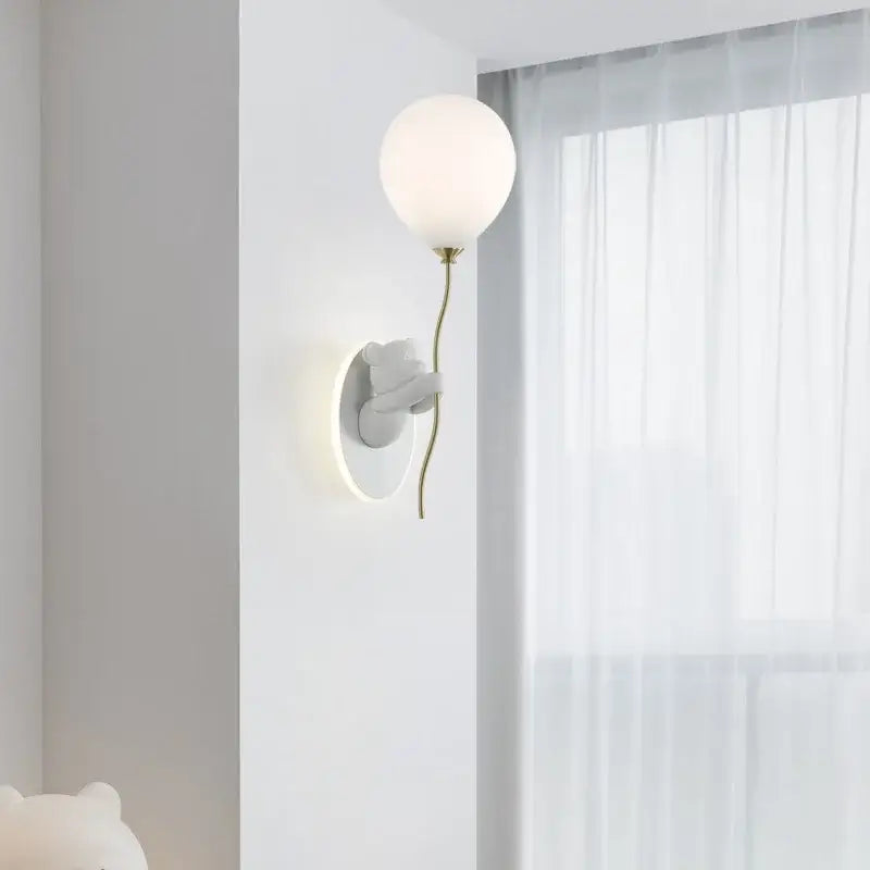 Gold cartoon bear balloon wall lamp with matte white glass bulb on sculptural gray ceramic base for kids decorbites cartoon bear
