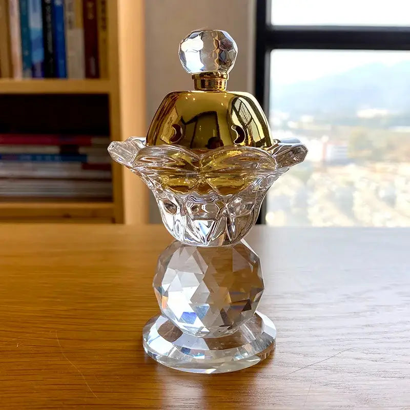 A clear crystal candle with gold-toned faceted cap and base, complementing crystal candle holder and metal incense burner decor
