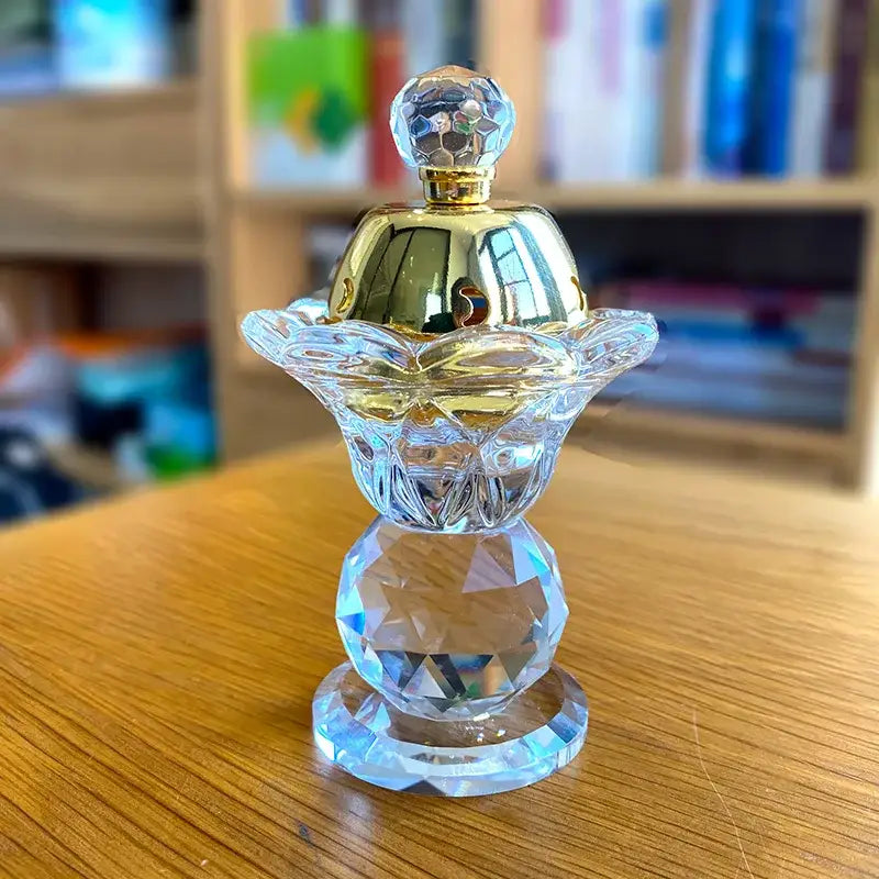 A clear crystal candle with gold-toned faceted cap and ornate floral detailing for dining room decor
