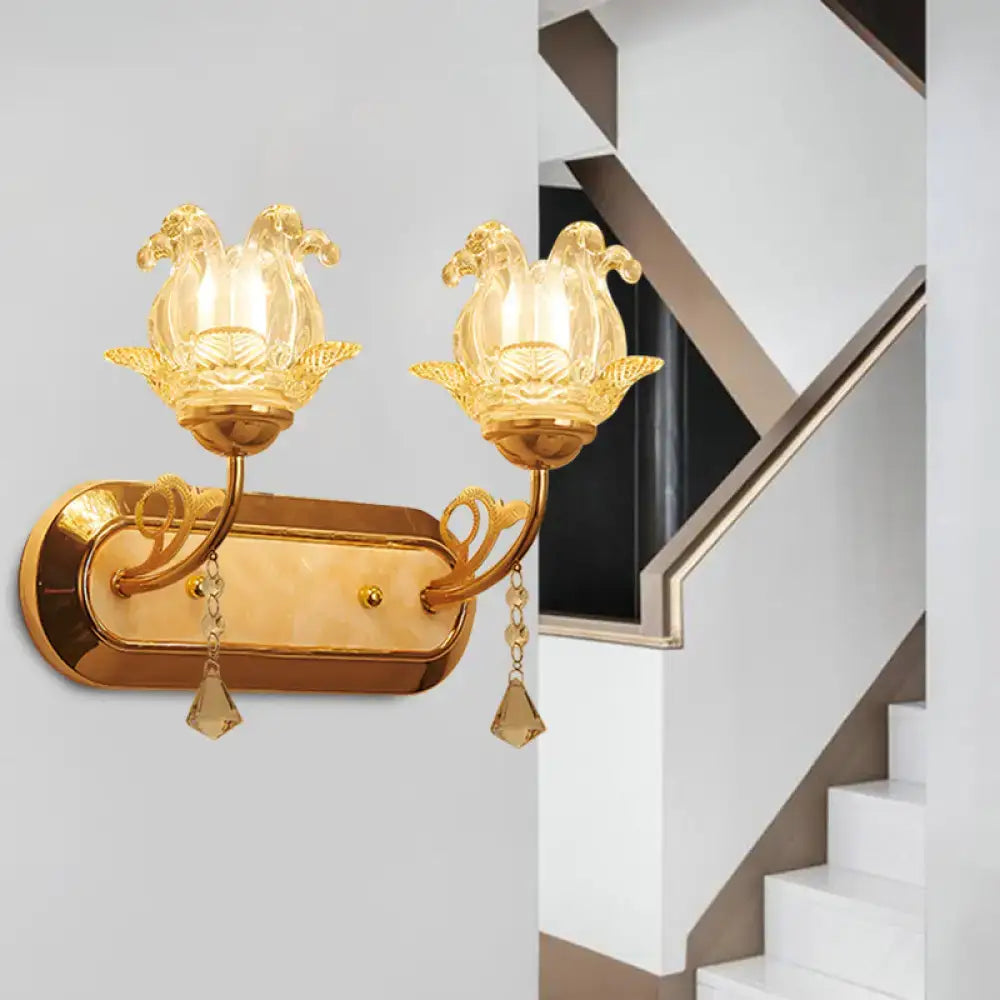 Gold-toned wall lamp with two lotus-shaped glass lampshades and crystal pendants featuring simplicity blossom design