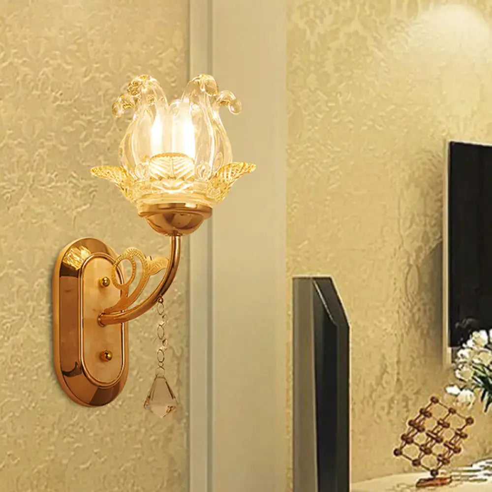 Gold-toned wall lamp with clear glass lotus-shaped shade and crystal droplet featuring simplicity blossom design and fixture width