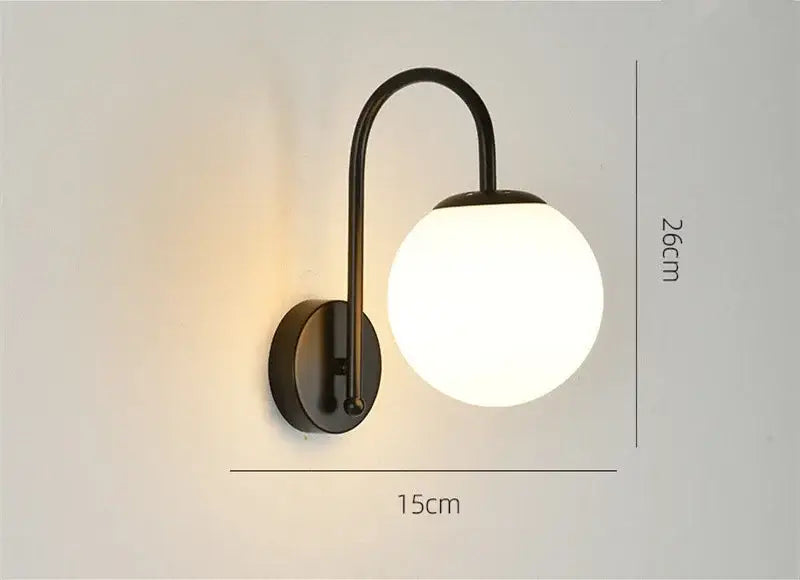 A sleek black wrought iron wall sconce with a frosted glass ball led shade from decorbites glass ball collection