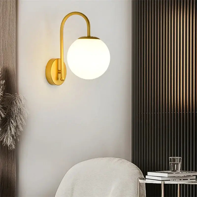 Gold-toned curved arm wall sconce with frosted glass ball led shade for bedroom decorbites glass ball lighting