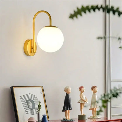 Gold-toned wall sconce with curved arm and frosted glass ball led globe for decorbites glass ball bedroom light