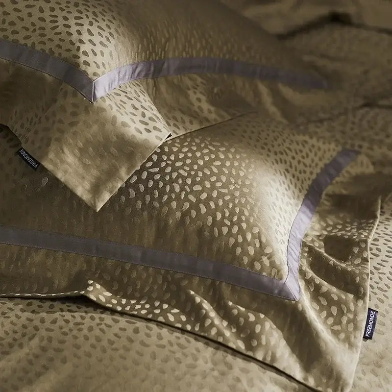 Gold-toned satin pillowcases with subtle spots and lavender trim in a gold and dark gray decorbites 100s egyptian cotton bedding set