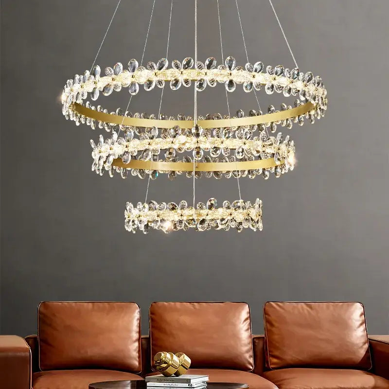 A modern gold decorbites crystal led chandelier with three-tiered metal rings and clear crystal droplets for living rooms