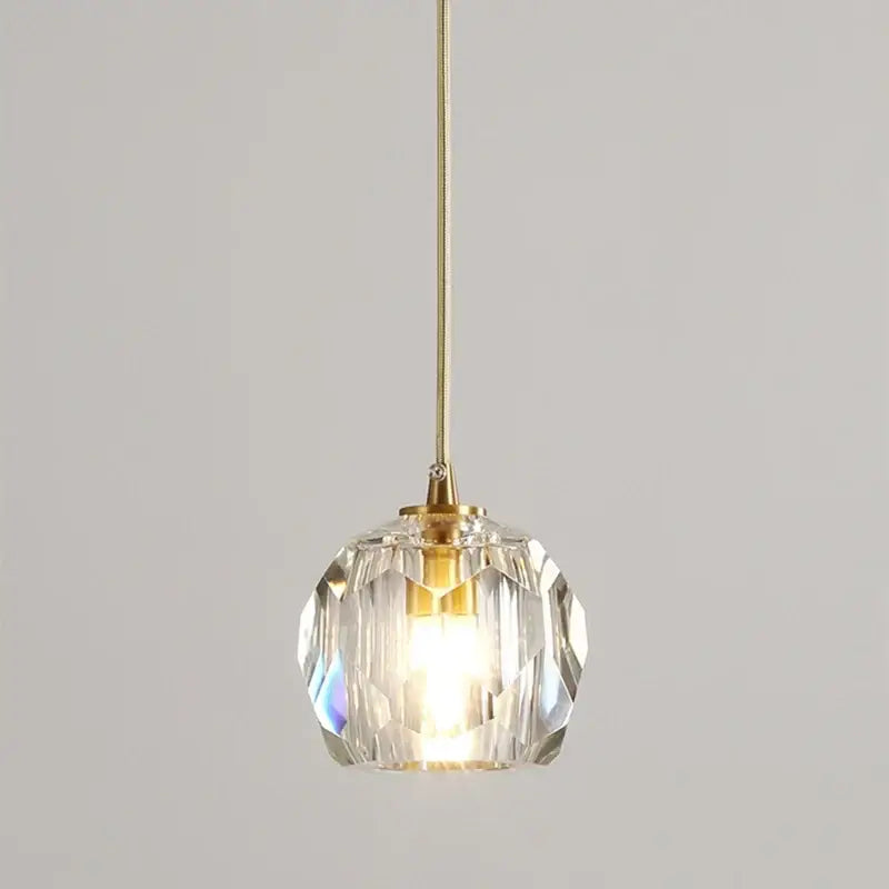 A clear faceted crystal copper led pendant light with gold toned metal fixture for dining room illumination