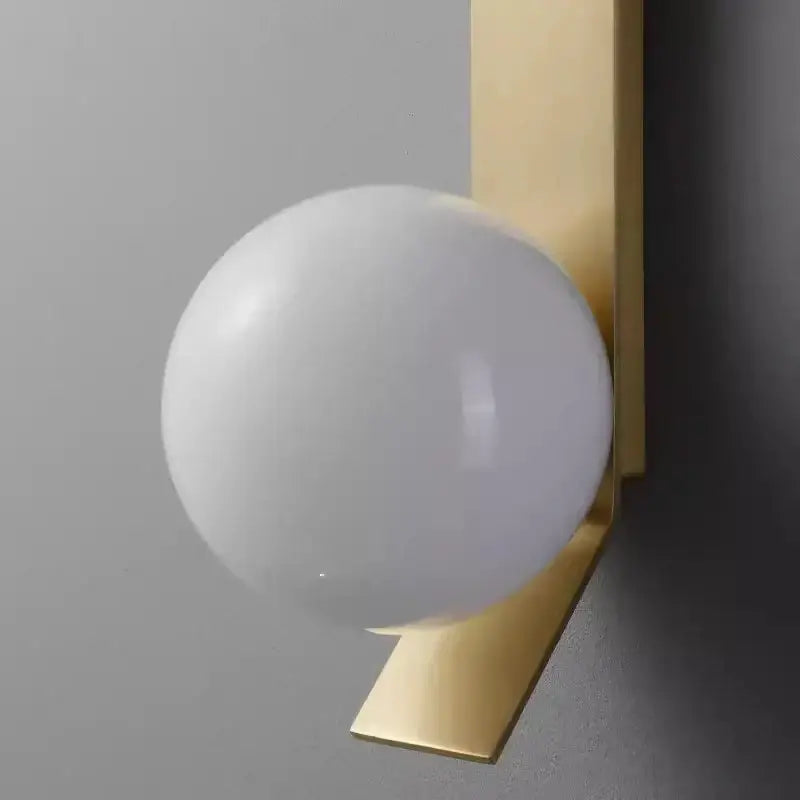 A sleek gold glass ball nordic wall lamp with frosted white glass globe and polished brass bracket for living room decor