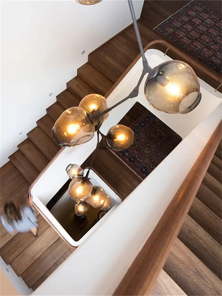 Modern brass-toned glass branching staircase chandelier with multiple spherical glass globes for dining room decorbites glass branching