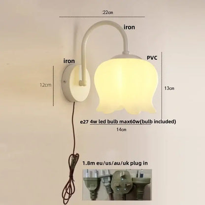 A soft yellow tulip-shaped iron led wall sconce with white iron base and curved arm for hallway decorbites iron led lighting