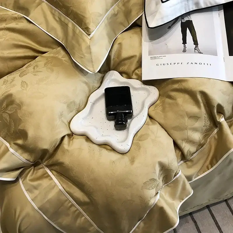 A sleek black perfume bottle on a white ceramic tray complements gold jacquard satin egyptian cotton patchwork bedding set decorbites