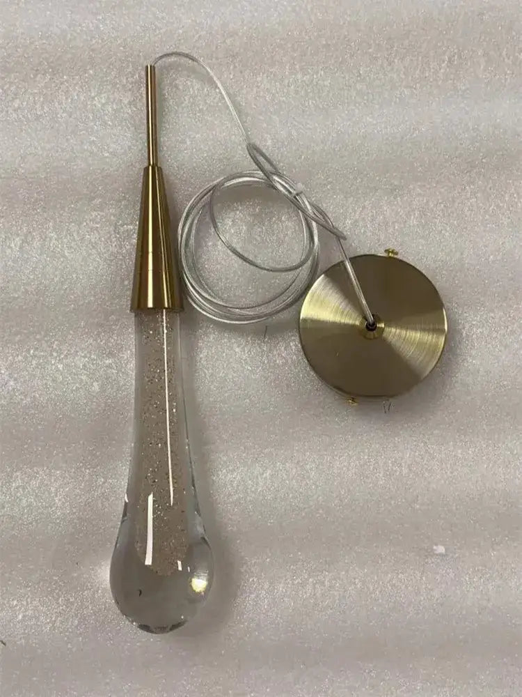 A gold liquid crystal drop pendant light with clear teardrop glass and gold-toned metal base for bedroom decorbites crystal drop