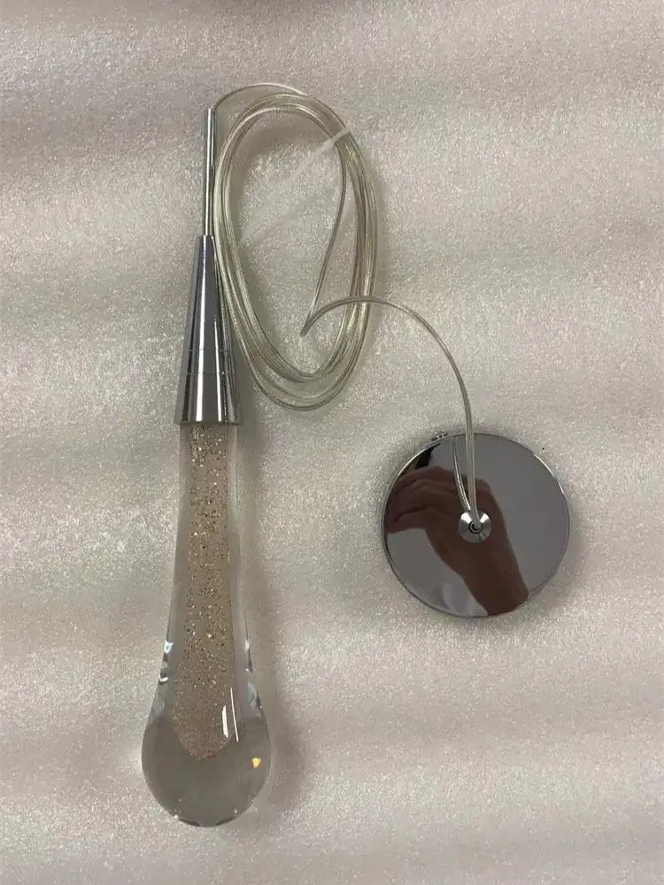 A gold liquid crystal drop pendant light with a sleek teardrop shape filled with glitter for bedroom decorbites crystal drop