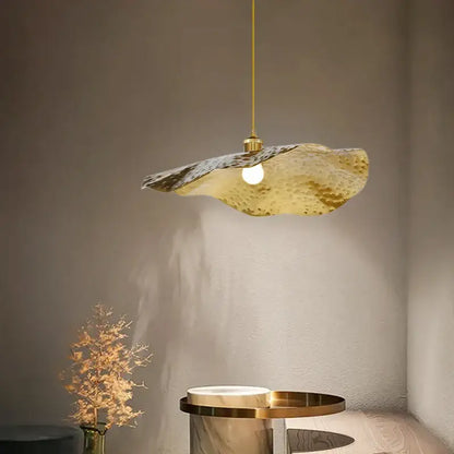 A modern hammered gold pendant light with an organic lotus leaf shape for decorbites gold lotus living room decor