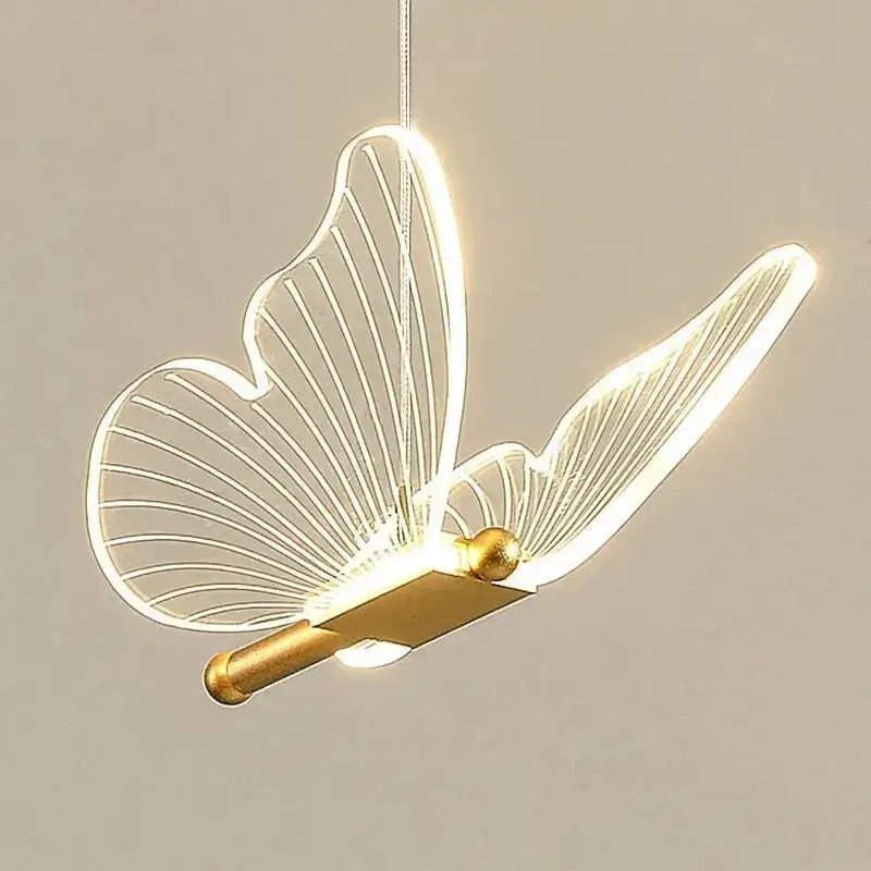 Gold metal butterfly metal pendant light with translucent wings and illuminated gold-toned body for bedroom decor