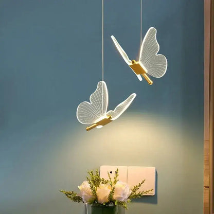 Two elegant gold metal butterfly pendant lights with translucent wings hang as bedroom decorative lighting