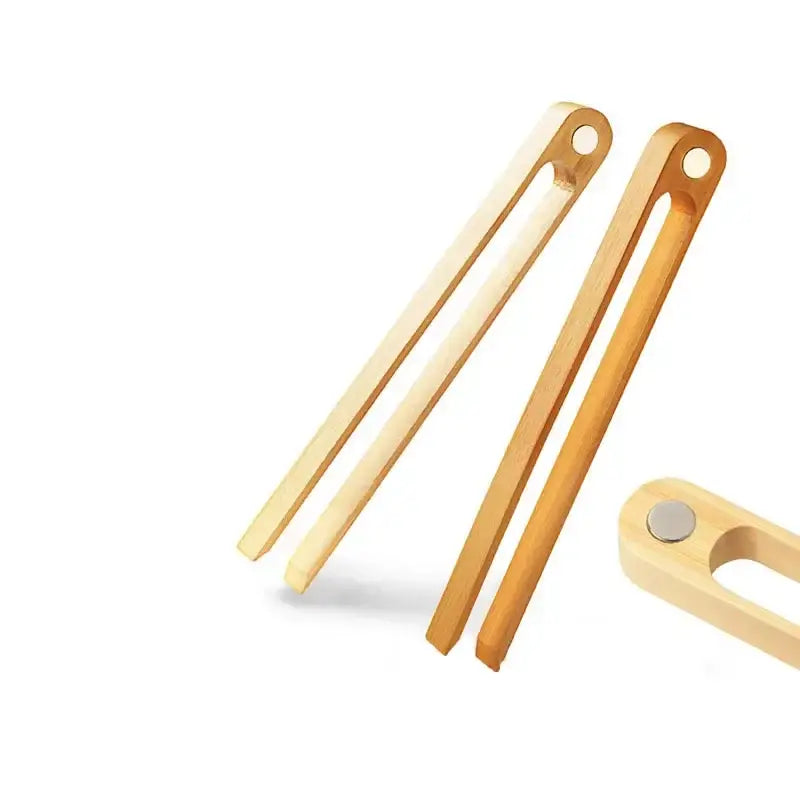 Light-colored bamboo toaster tongs with a smooth natural finish and rounded ends for kitchen bread use