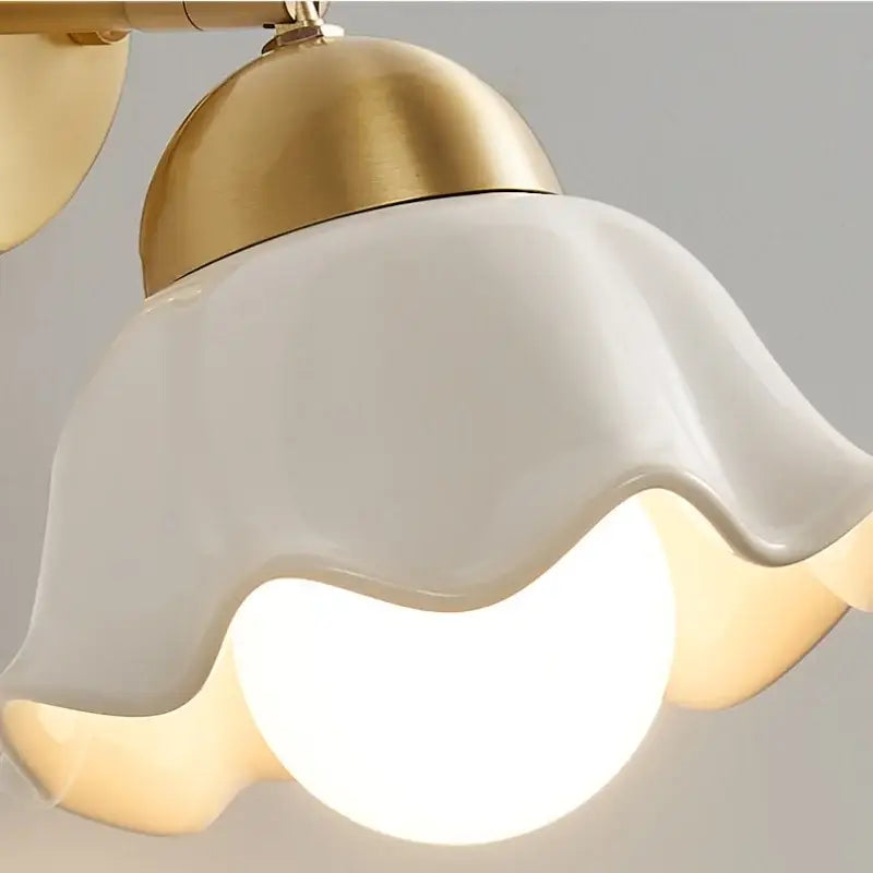 White ceramic wall light fixture with wavy petal design and gold-toned metal for bedroom pull chain lamp
