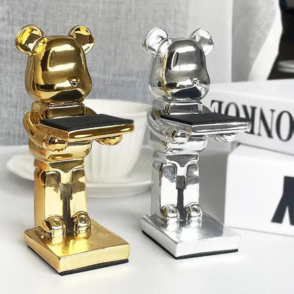 Two metallic gold and silver bear statue watch racks each holding a black tray for bedroom storage stand