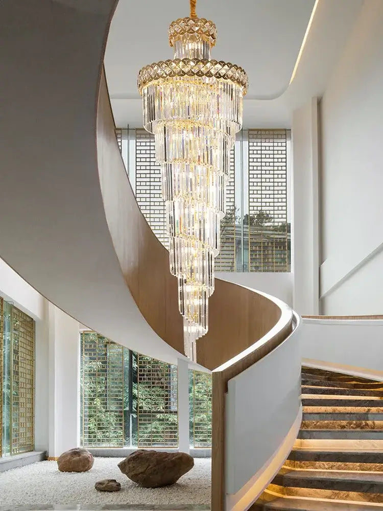 Gold stainless steel crystal pendant light with cascading prisms and gold accents above a modern spiral staircase decorbites gold stainless