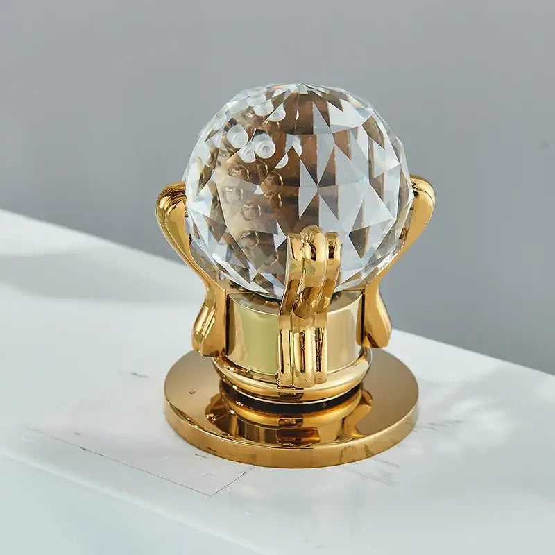 A decorbites gold swan bathroom faucet with a gold crystal globe handle in a polished metal frame and base