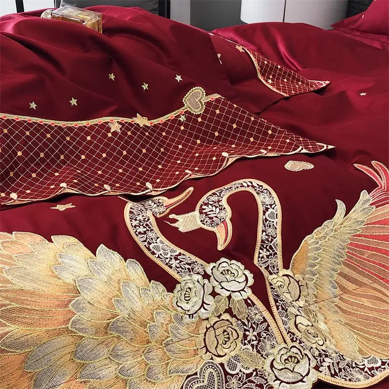 Deep red satin bedding set with intricate gold swan love embroidery and white lace floral motifs by decorbites gold swan